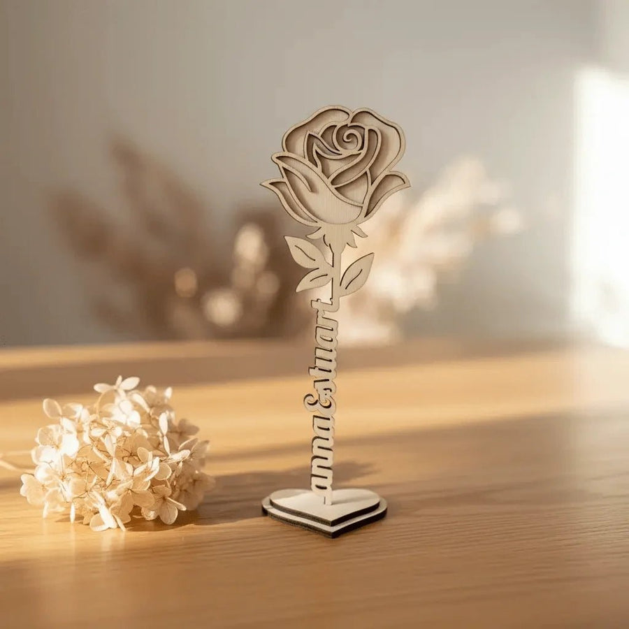 Rose aus Holz mit graviertem Namen am Stiel, auf einem Tisch mit Trockenblumen