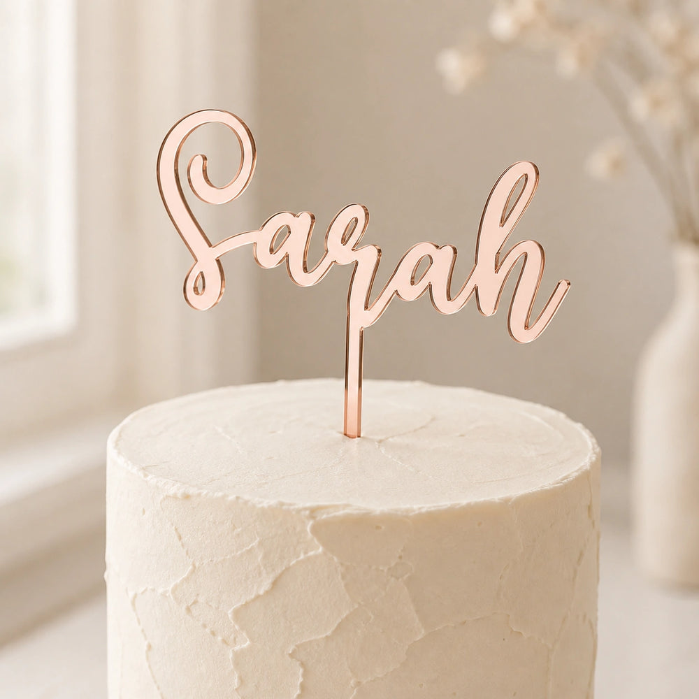 Cake Topper in Roségold mit Namensschriftzug steckt in einer schlichten weißen Torte