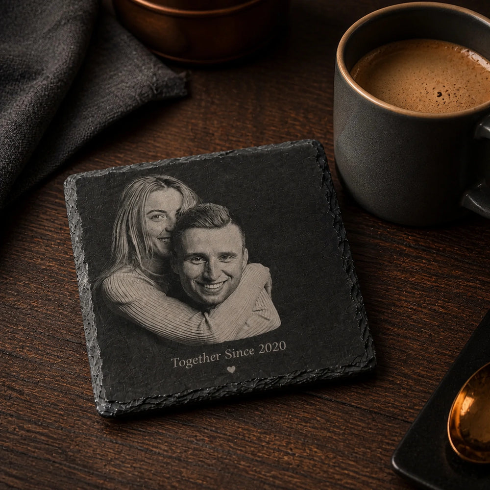 Untersetzer aus Schiefer mit Fotogravur eines Paares und Jahreszahl neben einer Tasse Kaffee