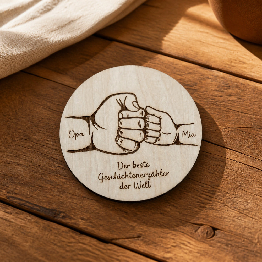 Runde Holzscheibe mit graviertem Faustgruß zweier Generationen und Namen auf rustikalem Tisch