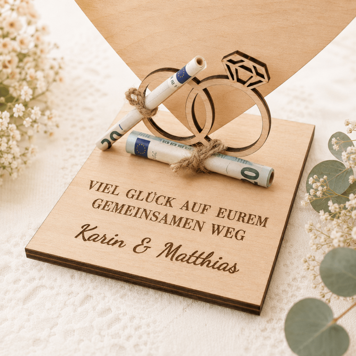 Detailansicht: aufgerollter Geldschein an den Holzringen des Hochzeitsgeschenks