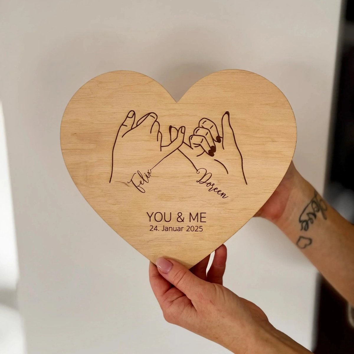 Holzherz mit Pinky-Promise-Motiv in der Hand gehalten