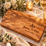 Olivenholzbrett mit Lasergravur Jasmini und Max, Eheringe und Hochzeitsdatum, auf gedecktem Hochzeitstisch