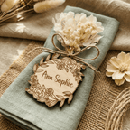 Rundes Namensschild mit Blütenkranz und Trockenblume auf Serviette